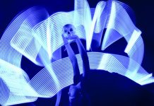 A girl arches backward, holding a skull aloft over her head. Waves of white light surround her.