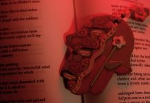 Red-tinted photograph of a clay hamsa atop an open book of poetry
