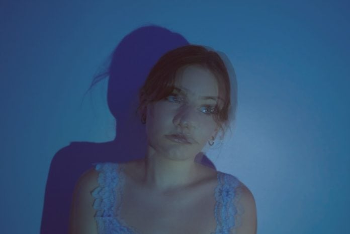 A blurry, blue-tinted photo of a girl who is looking off to the side.