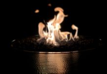 A fire burns in a bronze vessel against a black background.