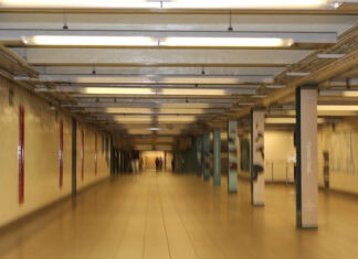 A slightly blurry scene of a well-lit, beige walled, underground station.