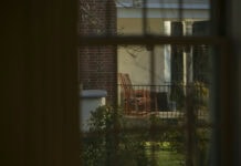 7:18 Gazing through a window, we look out on a porch with two rocking chairs, framed by greenery.