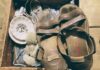 Shoes (circa 1940) A pair of brown leather sandals, stained with wear, sit atop a wooden crate filled with antique objects.