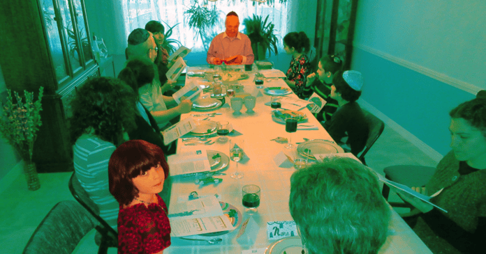 The author looks up from the table while her grandfather leads his last seder before his death in 2017.
