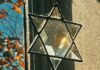 A crystal Jewish star hangs in a lit window, refracting the natural light.