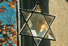 A crystal Jewish star hangs in a lit window, refracting the natural light.