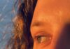 A close up shot of a woman's eyes looking to the side with the sun highlighting the lighter parts in her hair and eyes.