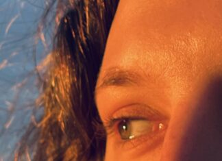 A close up shot of a woman's eyes looking to the side with the sun highlighting the lighter parts in her hair and eyes.