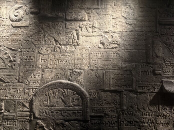 IMG_7594 Light streaks across a stone wall covered in Hebrew text and Jewish symbols with streaks.